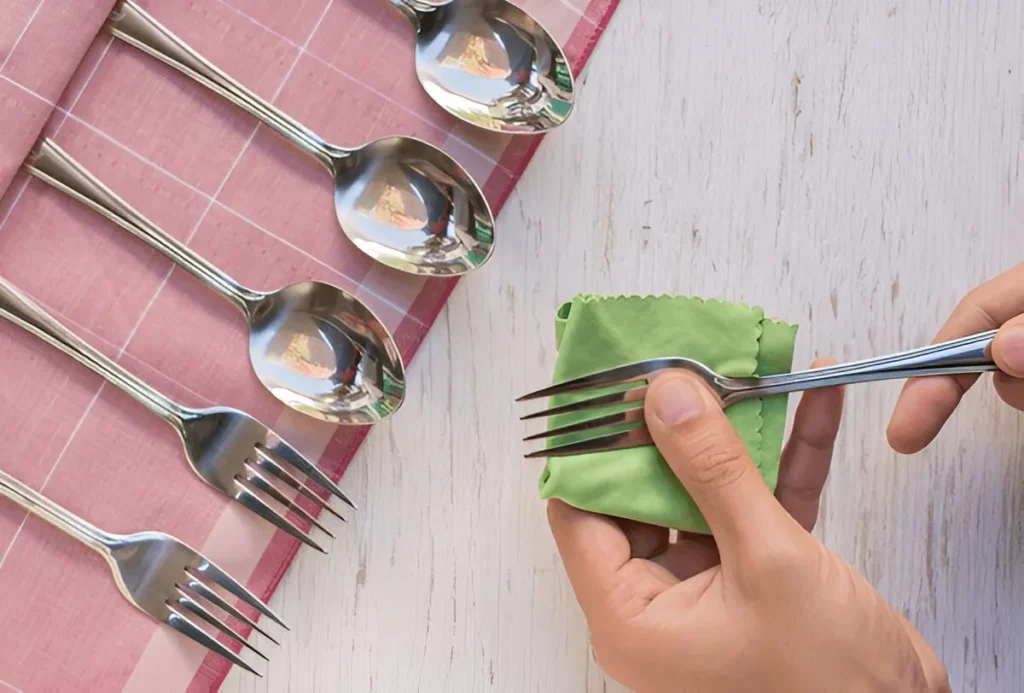 Human fingers are buffing a fork with polish cloth