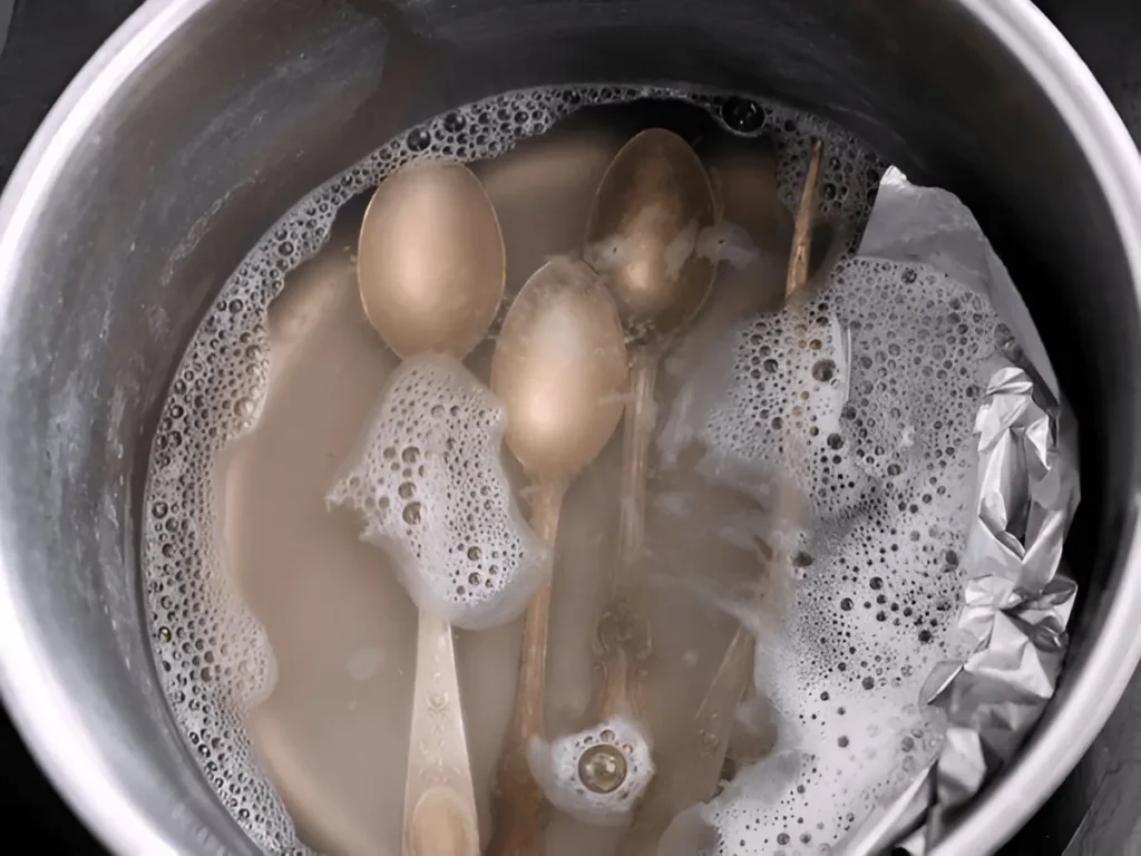 Cleaning of stubborn tarnish of silverware by putting it in boiling water soaked with baking soda in a pot