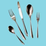 A 5 piece Sambonet flatware place setting on a blue background