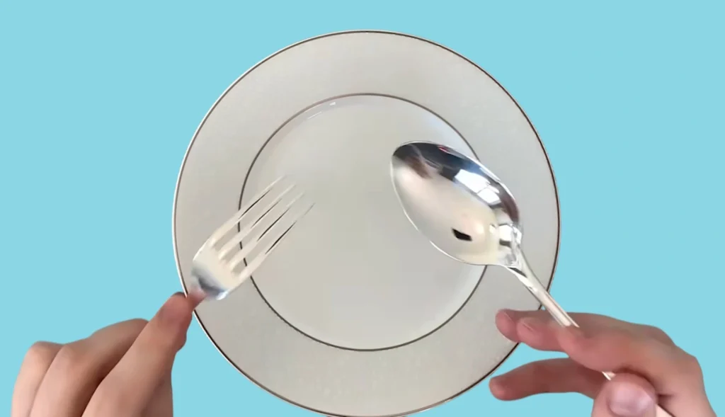 Two hands showing how to hold a fork and a spoon