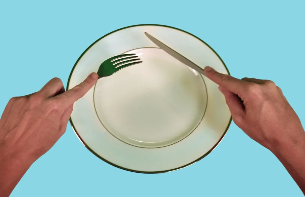 Two hands showing how to hold a knife and a fork