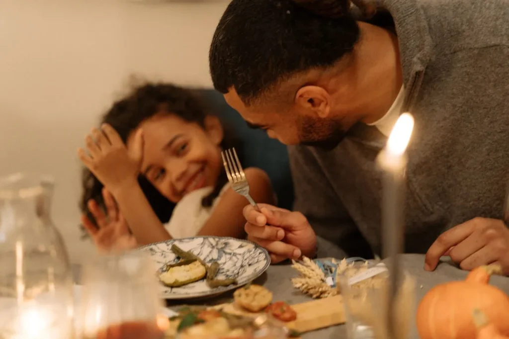A man and a kid enjoying a casual dinner using selverware