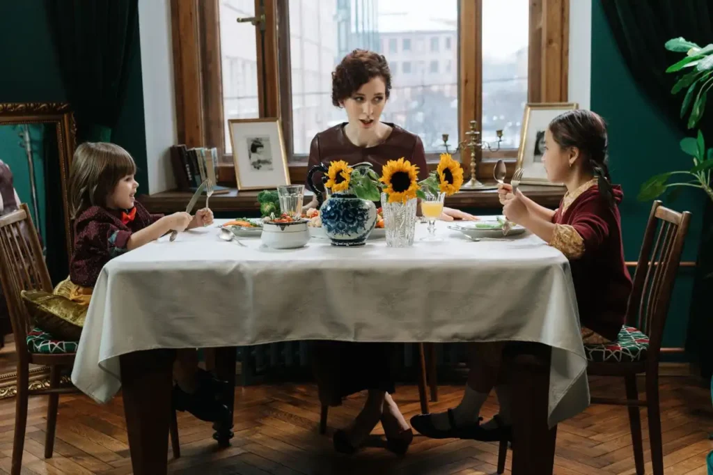 A lady and two kids using flatware while dining