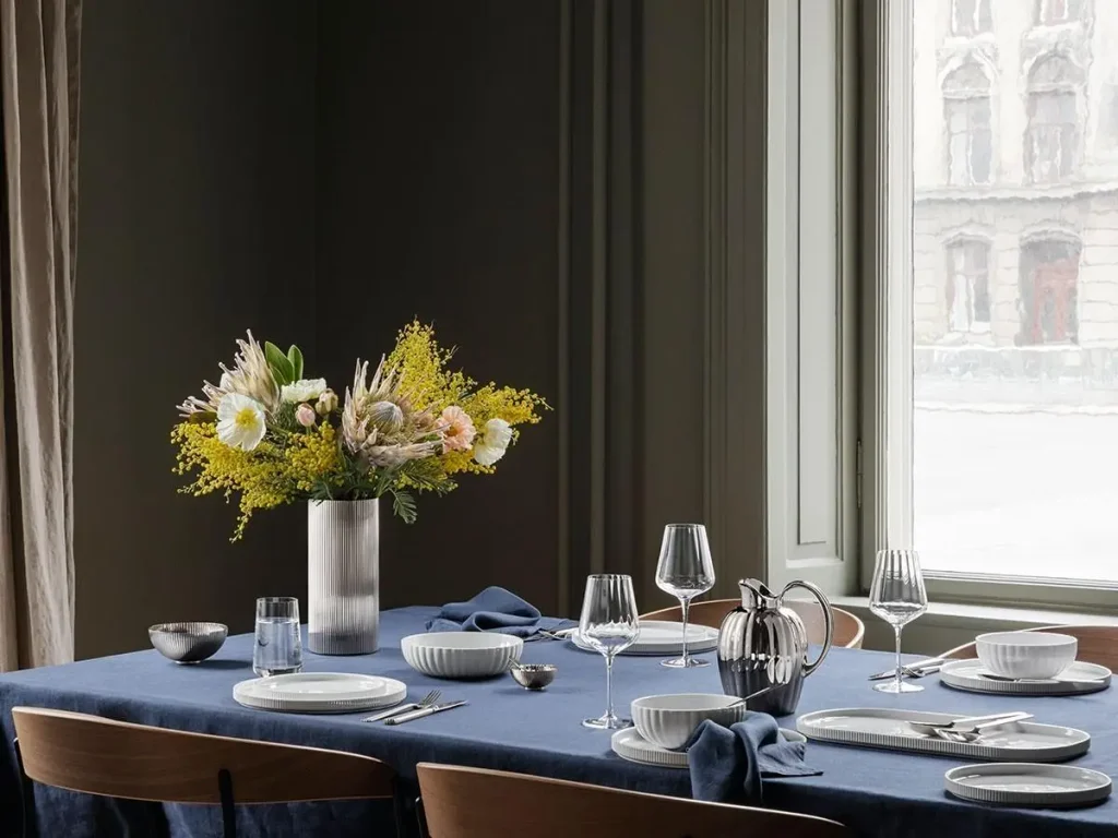 Elegant dinner table setting featuring Georg Jensen AJ cutlery, white porcelain plates, Nordic interior style