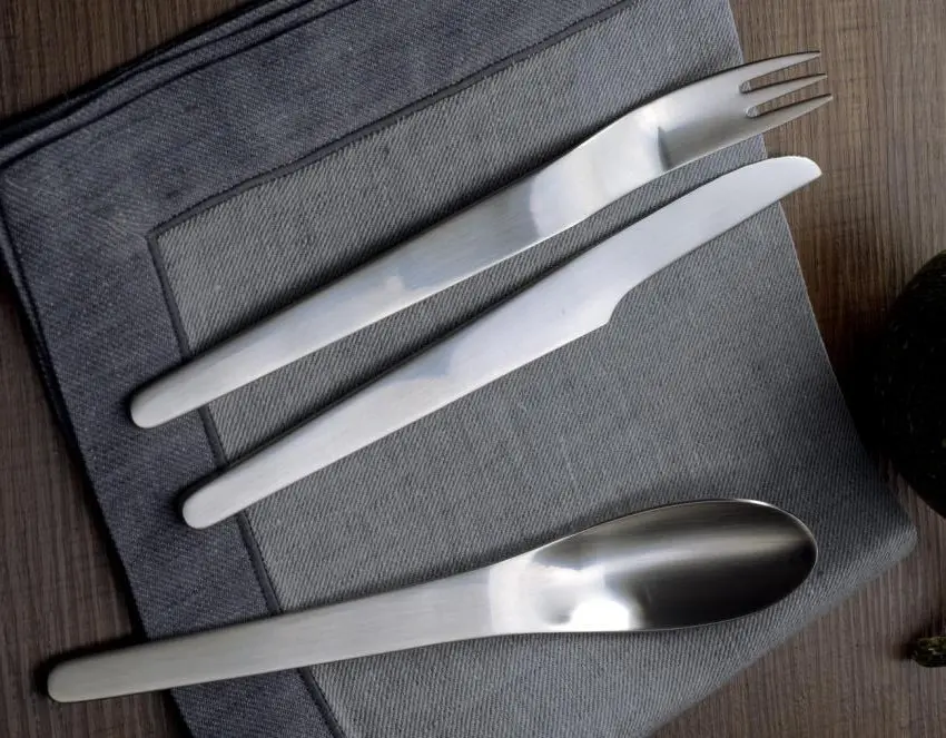 Close-up photograph showing brushed matte stainless steel texture and sculptural cutlery handles of Georg Jensen silverware